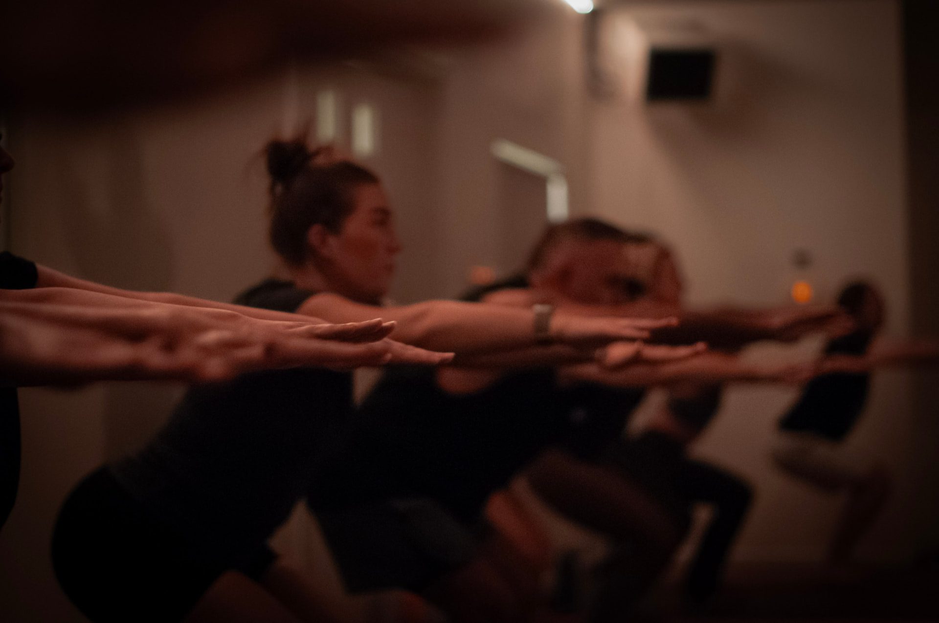 A row of practitioners held in chair pose, arms extended