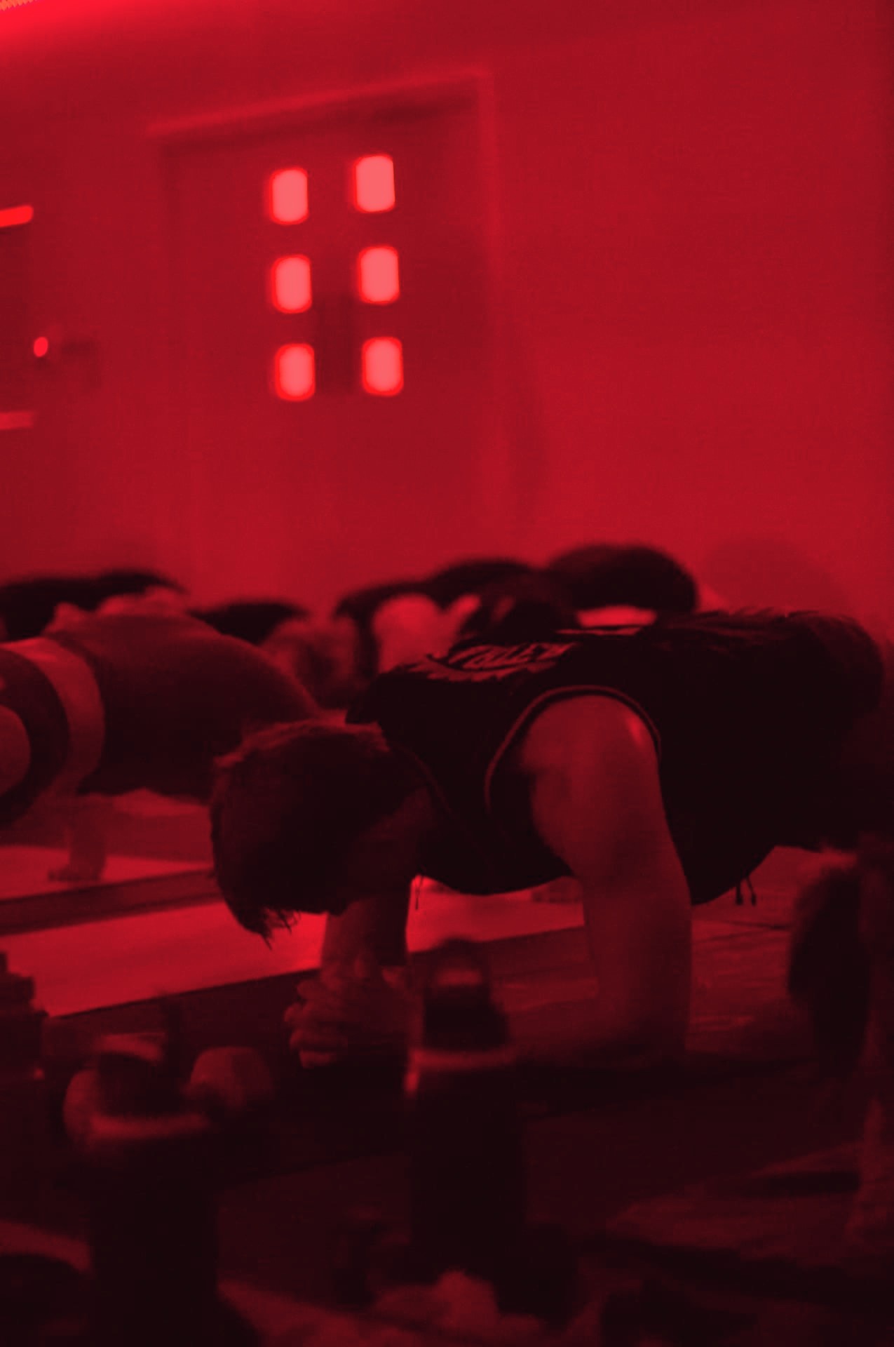 A man holding a forearm plank under red light