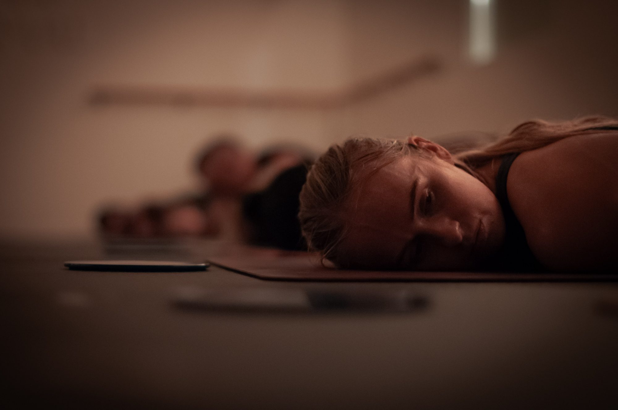 A student resting her cheek on the mat, the row softly blurred behind her
