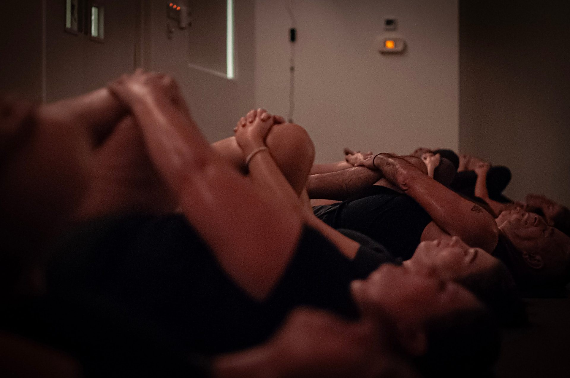 A line of practitioners hugging their knees to their chests at the end of class