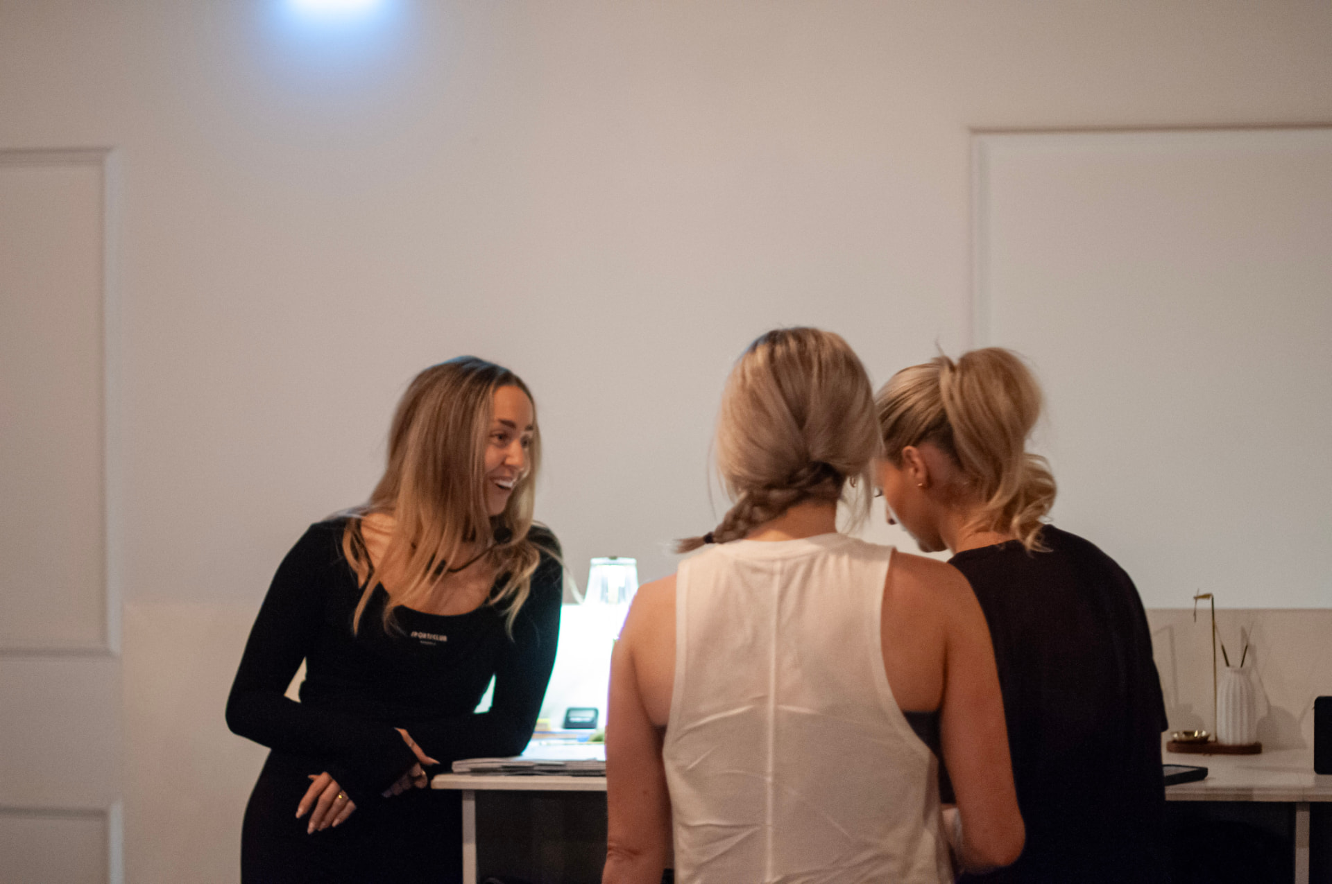 An instructor chatting with two new students at the studio reception desk