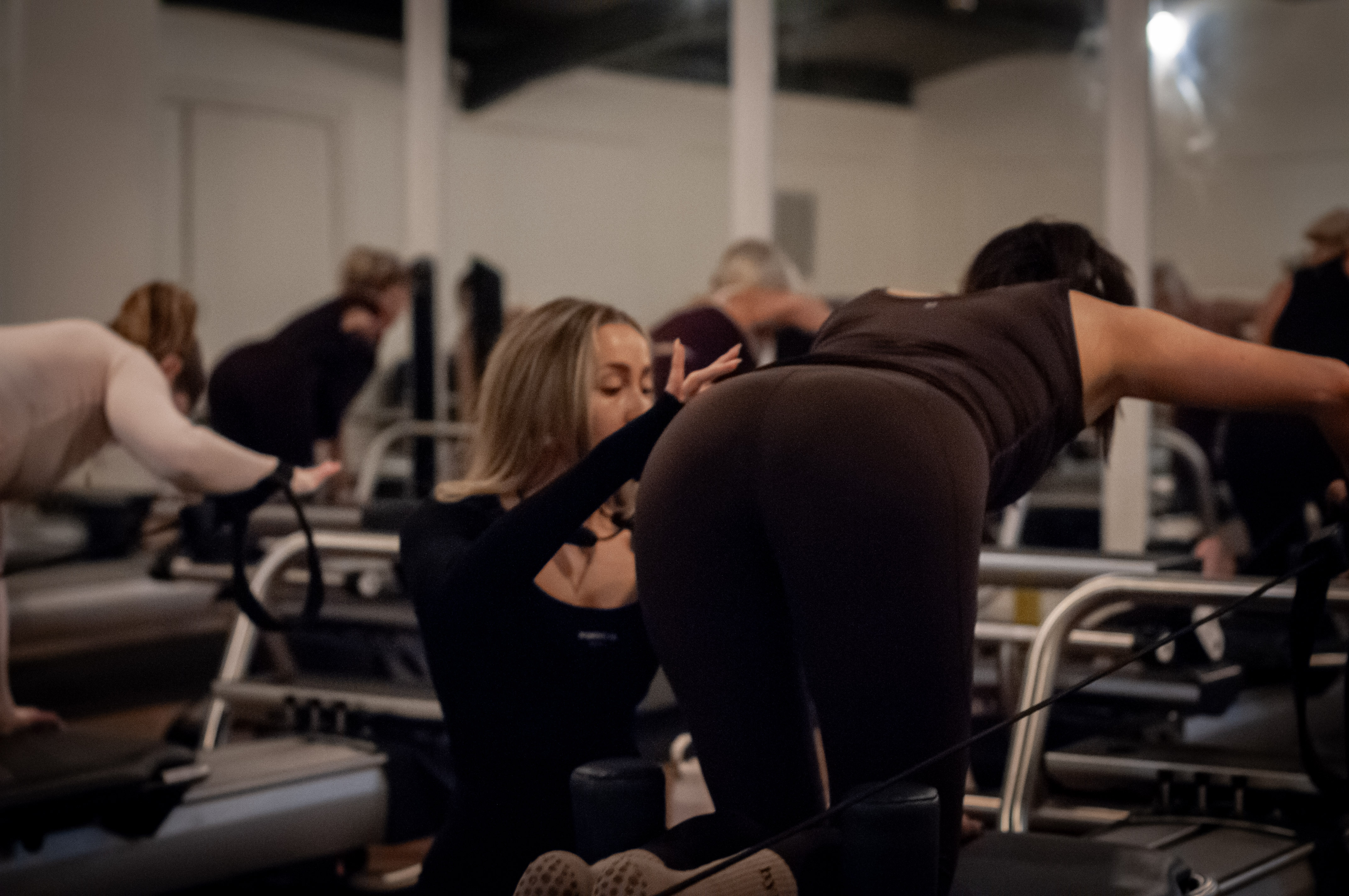 An instructor guiding students through a kneeling stretch on the machines
