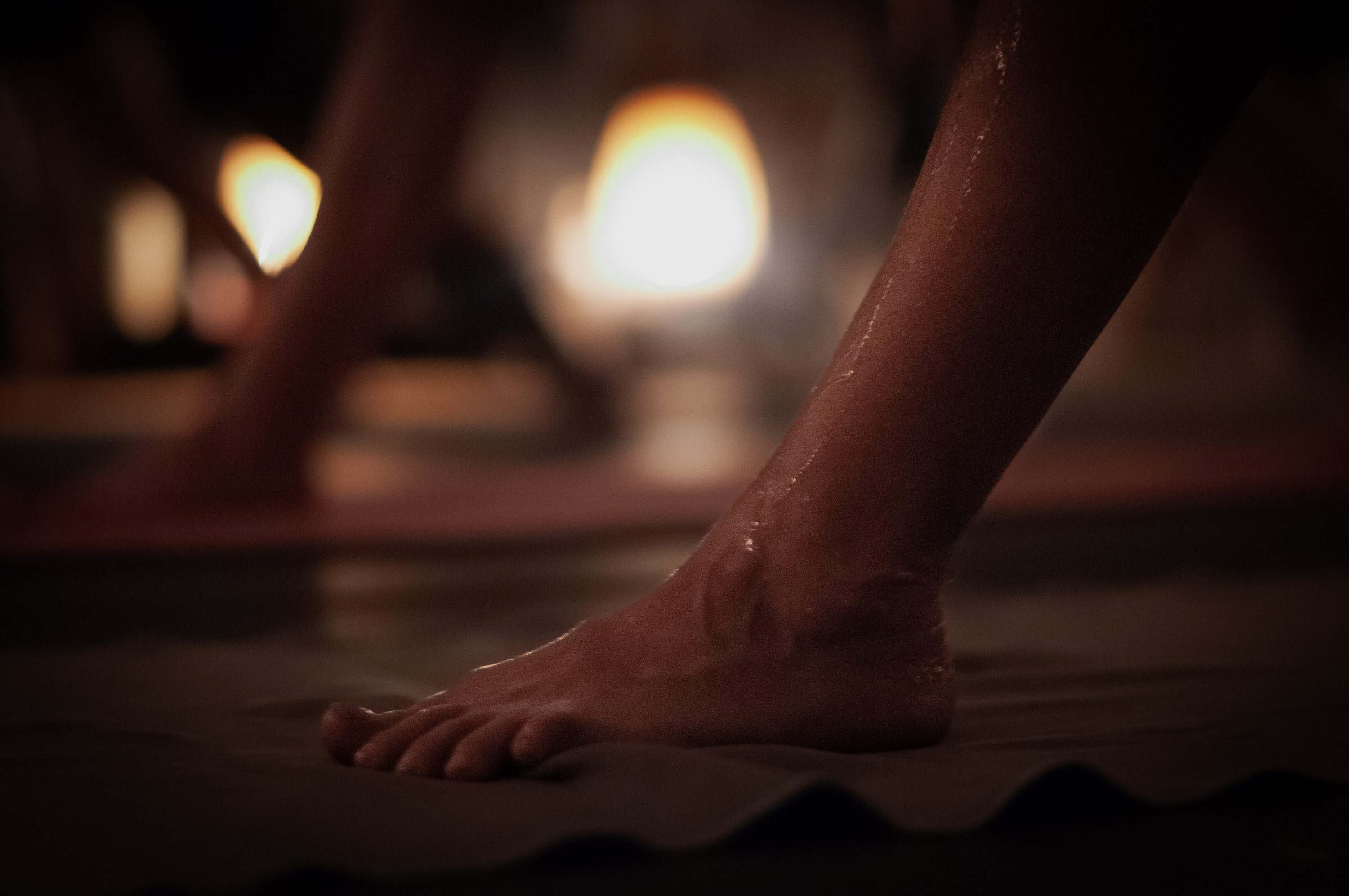 A sweat-beaded foot grounded on the mat beside a glowing salt lamp