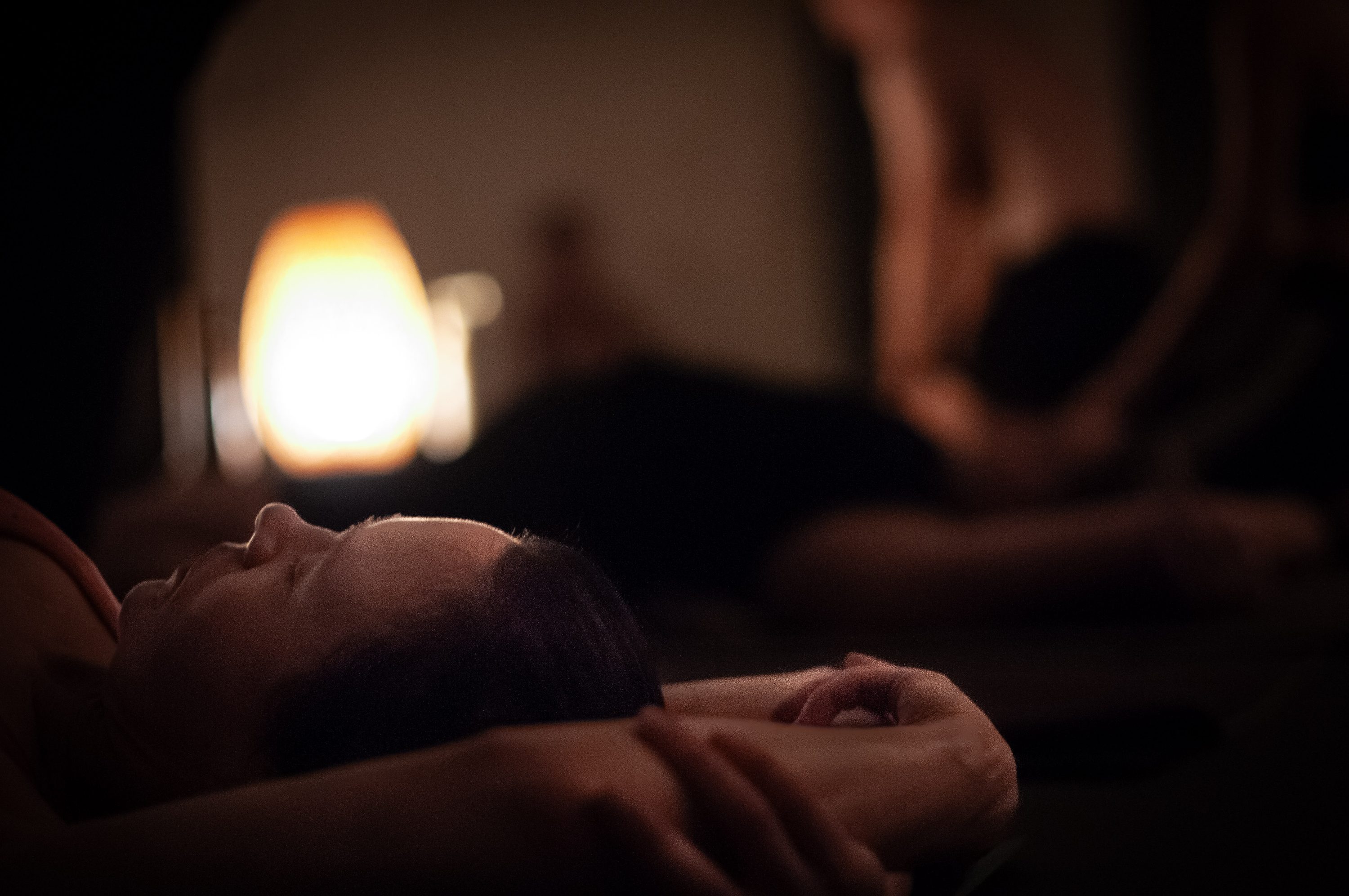 A student resting with eyes closed beside a glowing lamp